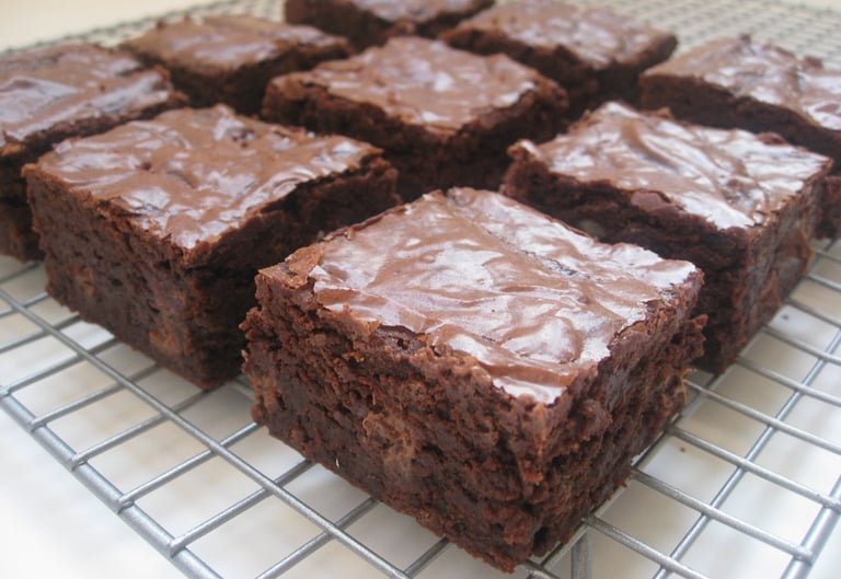 Freshly baked homemade chocolate brownies with a shiny crackle top cooling on a wire rack.