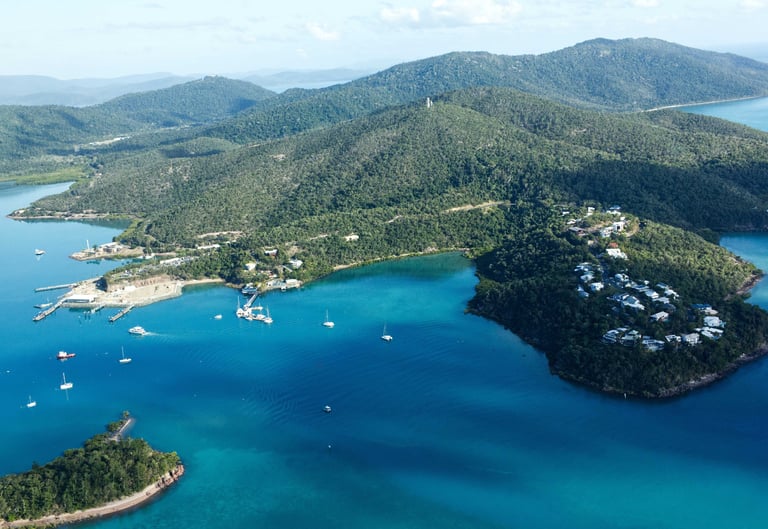 Aerial view of Hamilton Island with turquoise water, luxury resorts, and sailing yachts in the Whitsundays.