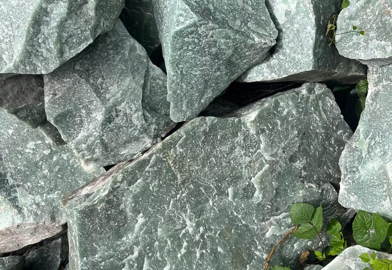 Rochas brutas de quartzo aventurina verde e minerais naturais em uma formação cristalina irregular.