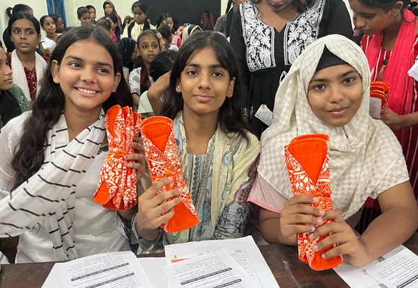 3 Schoolgirls holding up a Hanaru reusable sanitary napkin