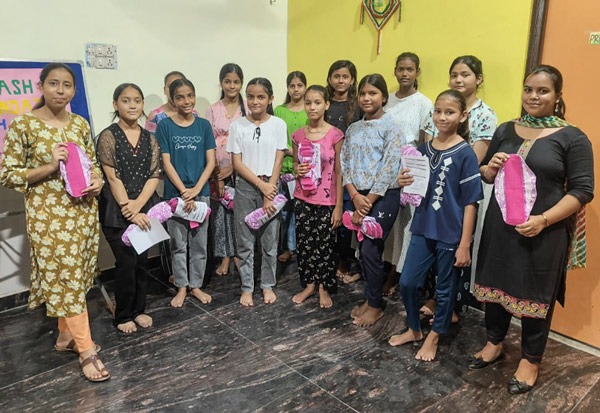 Small class of schoolgirls holding up a Hanaru reusable sanitary napkin