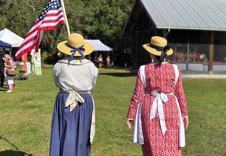Two women in 1860 dresses leading the parade one carrying US flag