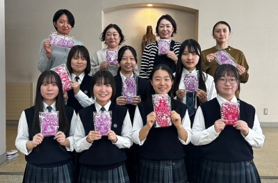Eleven teachers and school girls holding up Hanaru's sanitary napkins.
