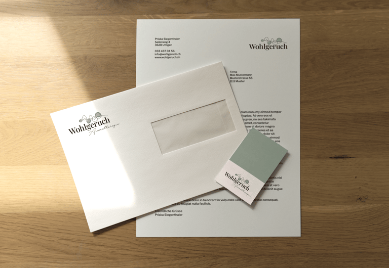 Briefschaft mit dem Logo von Wohlgeruch Aromatherapie auf einem Holztisch im Sonnenlicht.