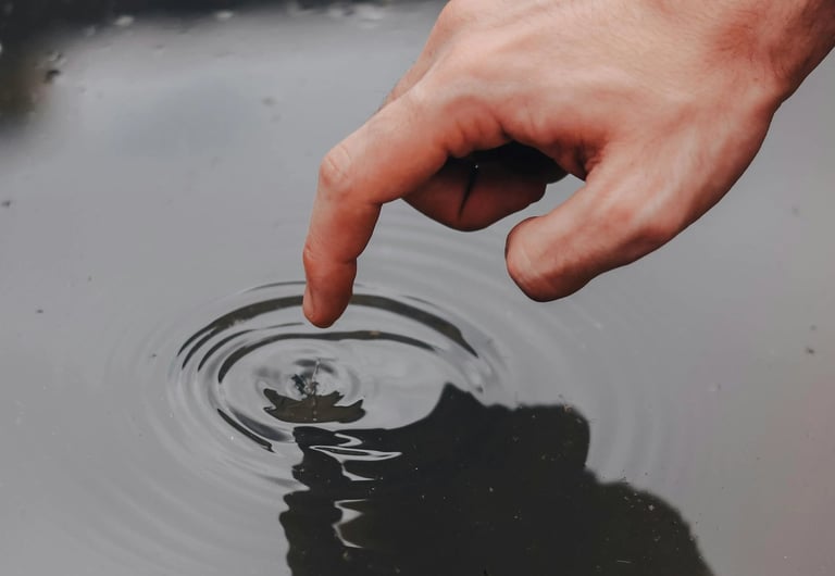 a person's hand is touching a water droplet