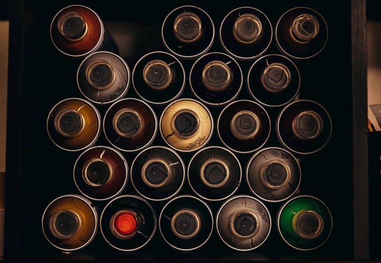 Top-down view of organized colorful spray paint cans in a storage box for graffiti art projects.