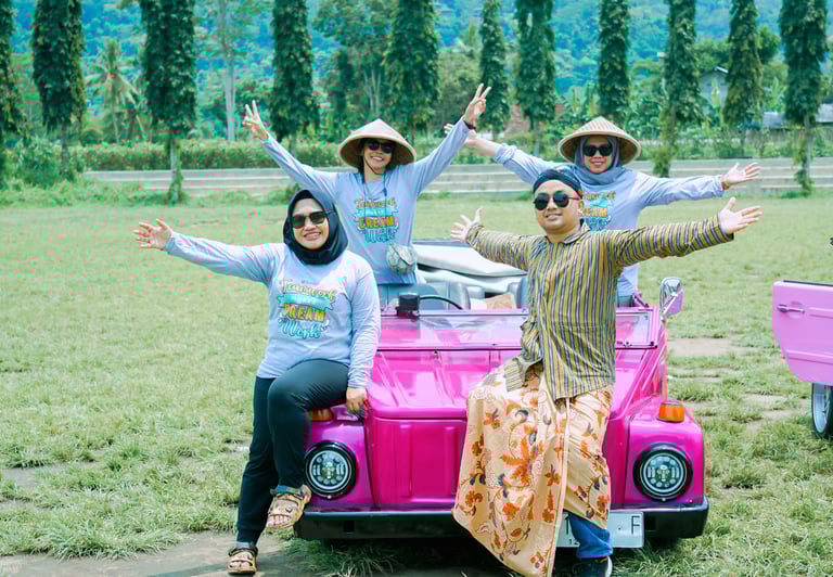 Wisatawan menikmati perjalanan VW Safari melewati pedesaan hijau dengan latar lapangan 