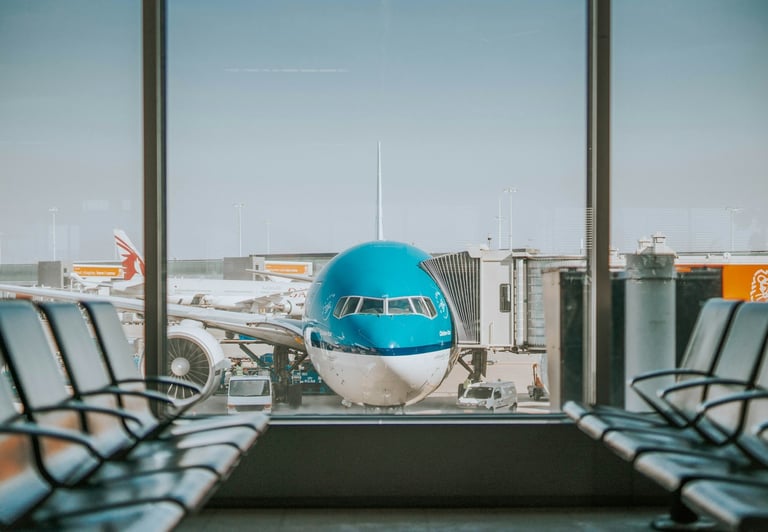 KLM aircraft at airport, viewed through large lounge windows from inside an airport