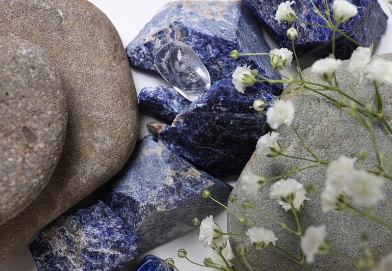 Cristales naturales de sodalita azul y piedras de río lisas con flores blancas de gypsophila