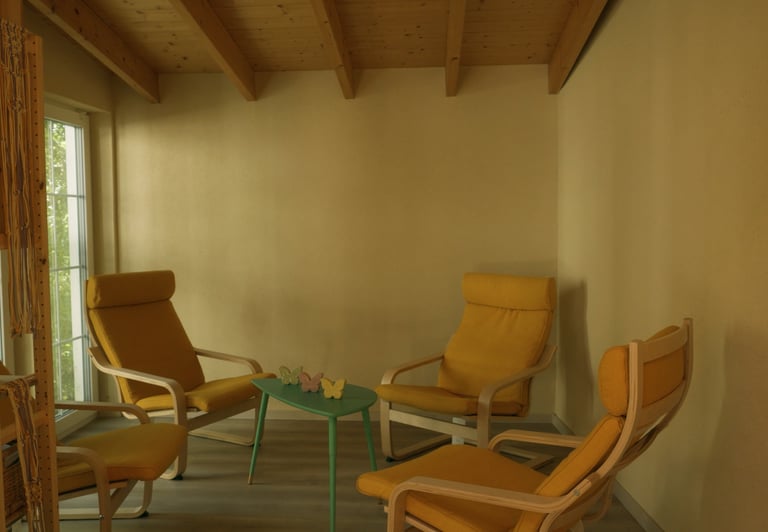 Gemütlicher Innenraum mit vier gelben Sesseln und einem kleinen grünen Tisch unter einer Holzdecke.