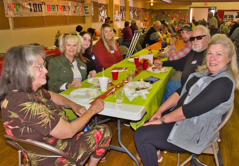 a group of people sitting at a table with plates of food