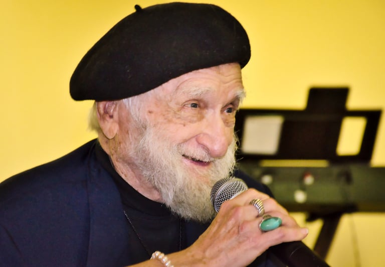 a man with a hat speaking to audiences with a microphone