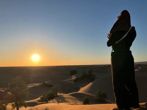 Desert camp fire at dusk with Moroccan tea tray in foreground and Sahara trek tent in background