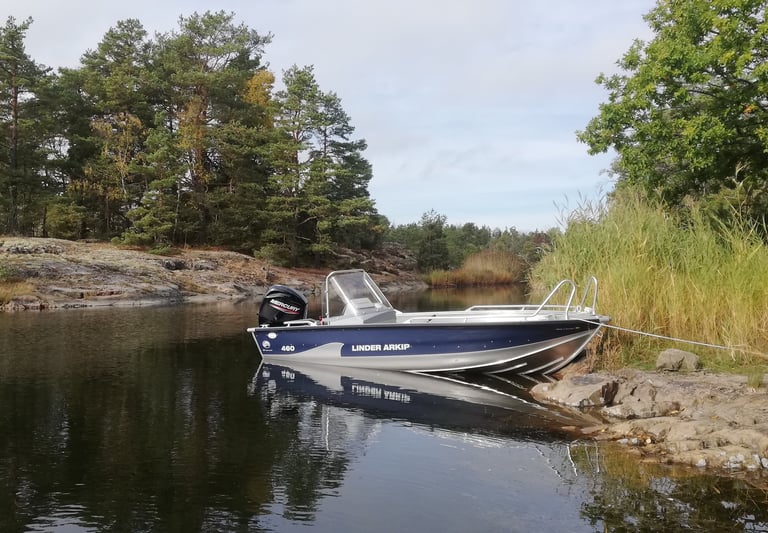 there is the boat "linder arkip" from fishing escape sweden on a lake in sweden. there are pine tree