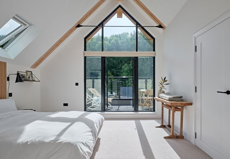 Loft conversions - a bedroom with a large window and a bed