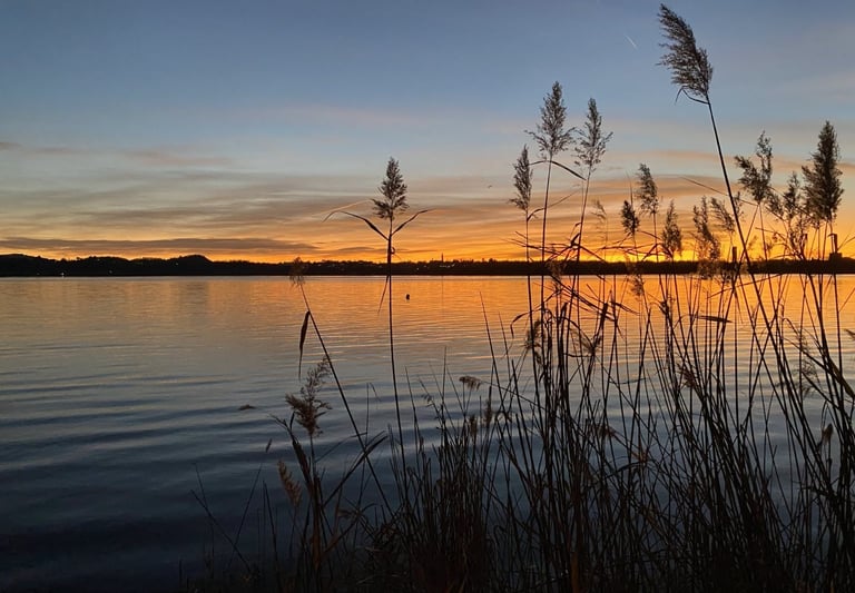 Sunset over Lake Oggiono with warm reflections on the water."