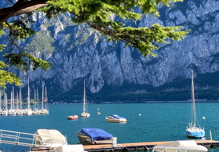 Sailboats gliding on Lake Como with mountains in the background.