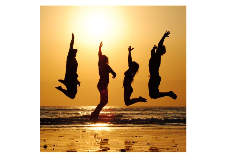 sur une plage au couché du soleil un groupe de personnes sautant en l’air.