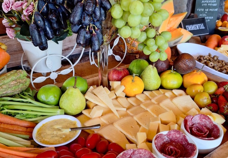 A gourmet charcuterie board featuring artisan cheeses, fresh grapes, berries, and sliced vegetables for a party.