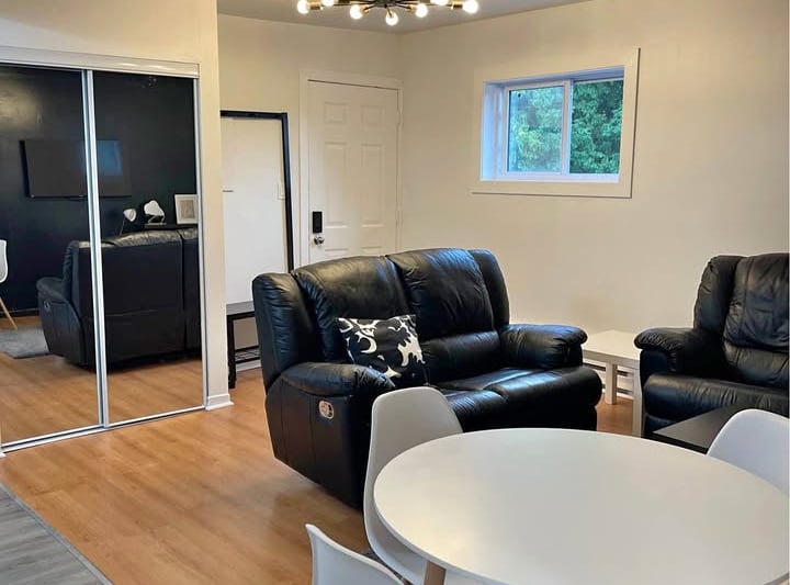 a living room with a table and chairs, mirrors closet and TV