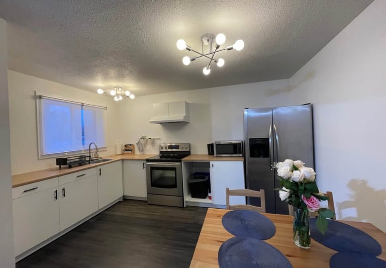 a kitchen with a table and chairs and a vase with flowers, kitchen layout with double fridge