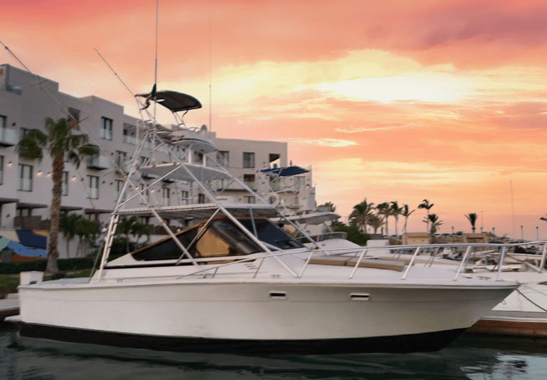 a boat in the water with a pink sky and buildings in the background