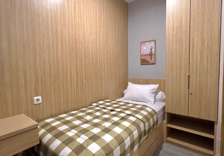 Kamar kos eksklusif di Surabaya dengan kasur single, lemari kayu, dan desain modern
