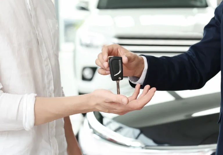 Remise de clés entre deux personnes devant une voiture blanche, symbolisant la vente ou la livraison