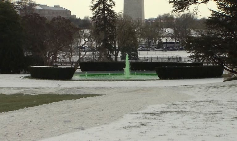 fountain with green water for Saint Patrick's Day in a snowy landscape.