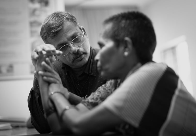 A doctor examines a patient's arm while listening attentively during a consultation in a clinical setting.