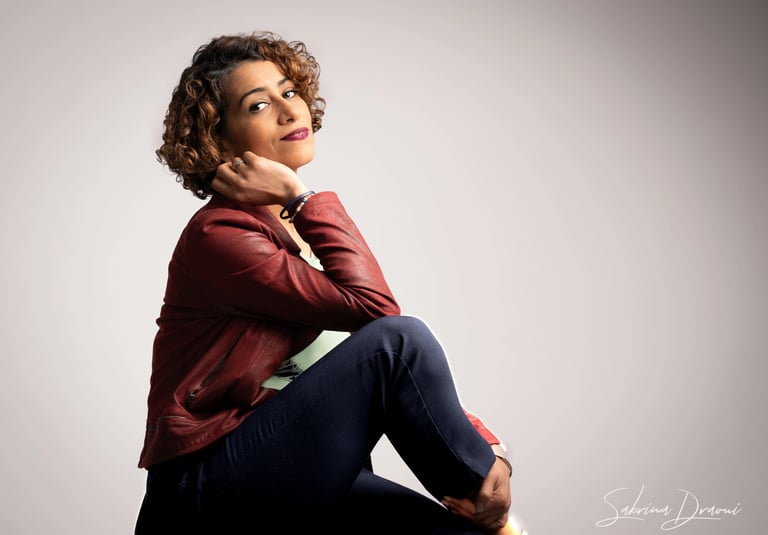 a corporate woman sitting on a stool with her hand on her chin