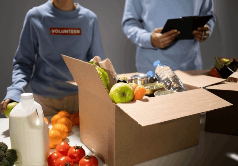 Voluntarios llenando una caja de donaciones con productos y alimentos para un banco de alimentos
