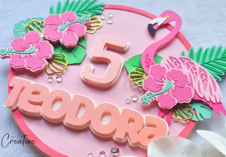 Round cake topper with pink flamingo, flowers, number 5 and a name Teodora on it