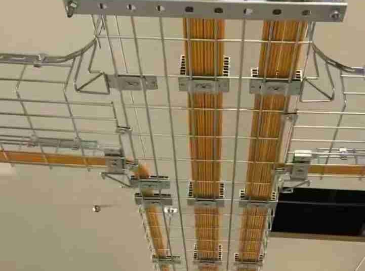 a metal wire mesh cable tray hanging in the ceiling with yellow cables