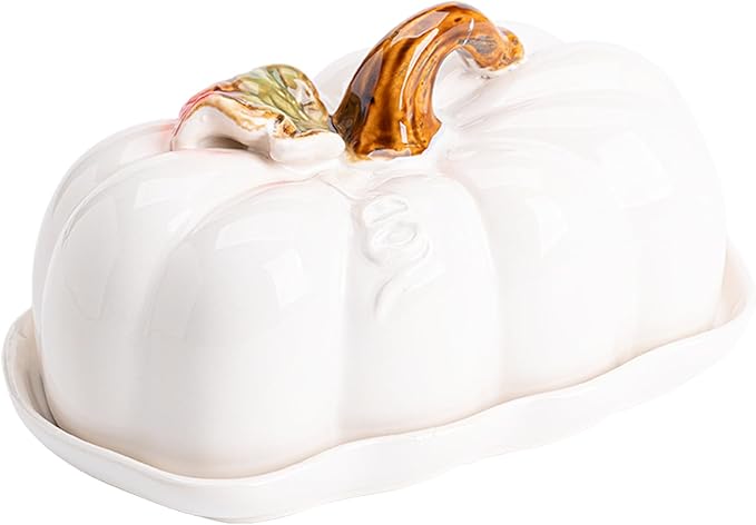 A white ceramic pumpkin shaped butter dish with a brown pumpkin stem and a green leaf as the top handle.