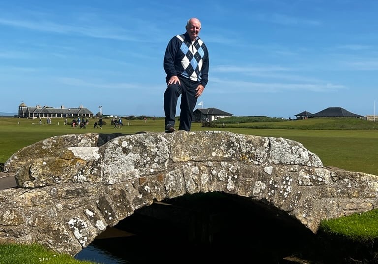 a man standing on a stone bridge over a stream