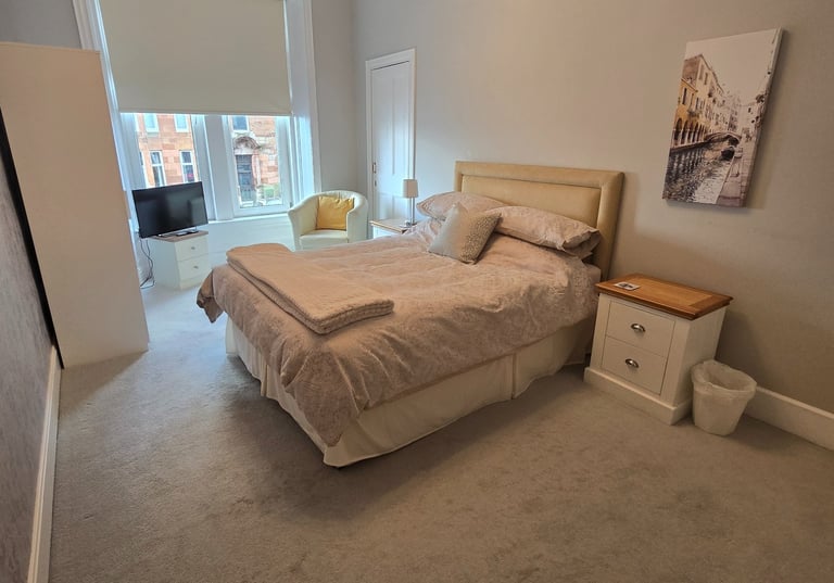 A large bedroom at Gourock Seaview Holiday Let with a kingsize bed and a chair