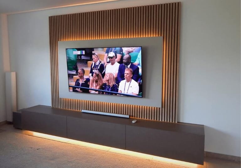 Modern living room entertainment center featuring a wall-mounted TV on a wood slat accent wall with LED backlighting.