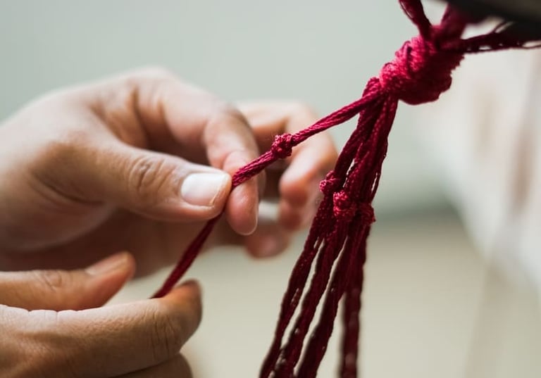 manos atando intrincados nudos de macramé rojo para un proyecto de artesanía textil hecho a mano