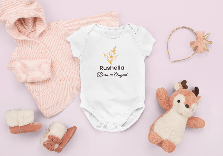 Flat lay of a personalised white baby grow with a red rose and 'Born in June' text, surrounded by so
