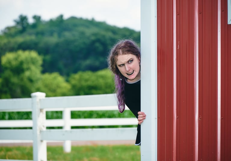 a girl with purple long hair looking out over a barn house with evil expression