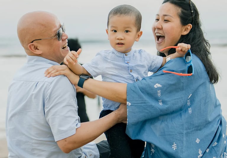 Parents laughing with their son during a candid family photography session at Nusa Dua Beach