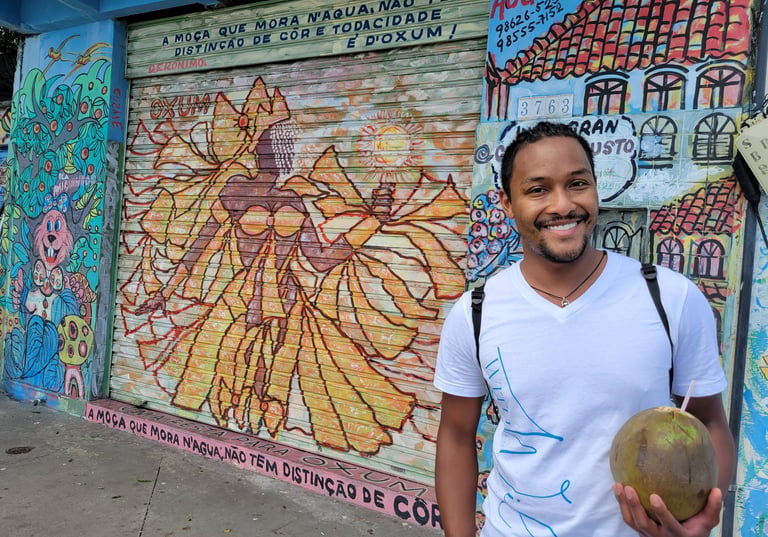 Wil smiling with a coconut in hand in Salvador in front of a drawing of Oshun