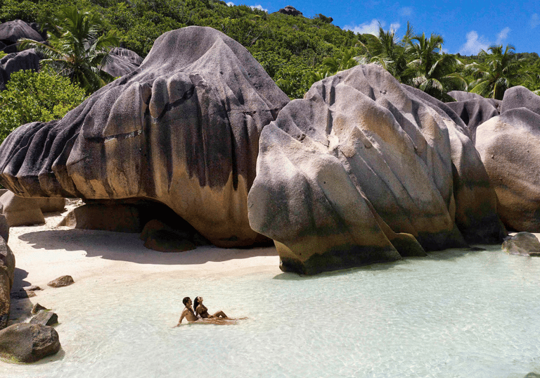 Guests relaxing on white sand beach next to giant granite boulders (photo courtesy of Expedia)