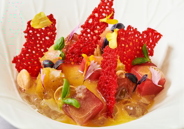 Vibrant fine dining dish with red crisps and edible flowers.