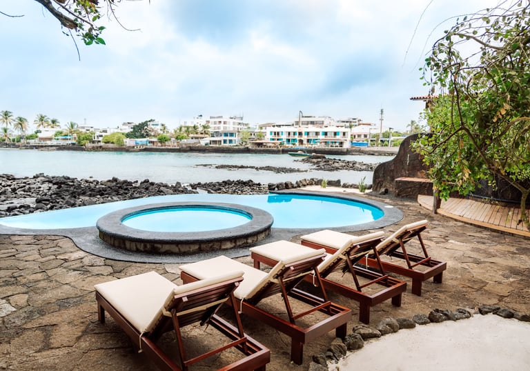 Oceanfront swimming pool and sun loungers at Villa Escalesia Galápagos, overlooking the rocky coastl