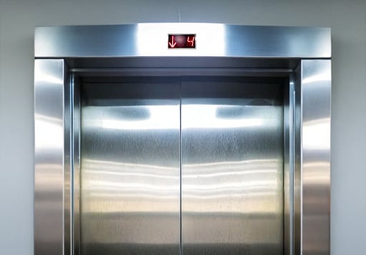 hallway elevator door and surrounding frame cladded in stainless steel