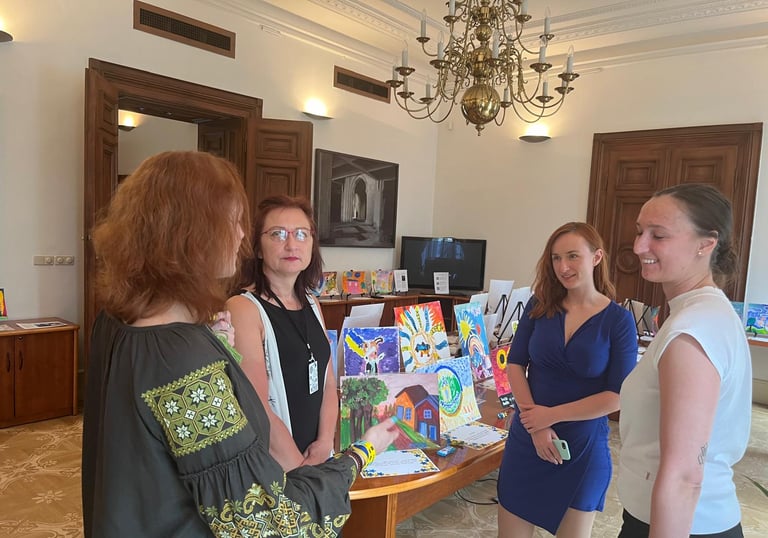 People discussing the exhibit of paintings by kids displaced by war