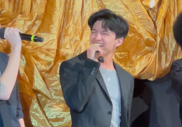 young male singer smiling and  singing into microphone