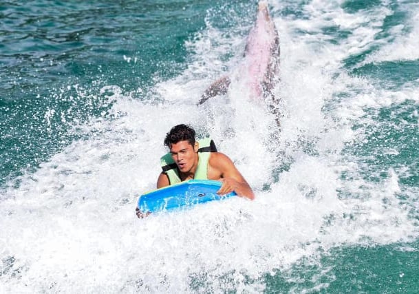 a man riding a surfboard in the ocean dolphines punta cana